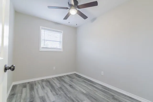 an empty room with a window and a fan