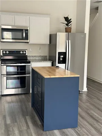 a kitchen with stainless steel appliances a stove a microwave and a hard wood floors