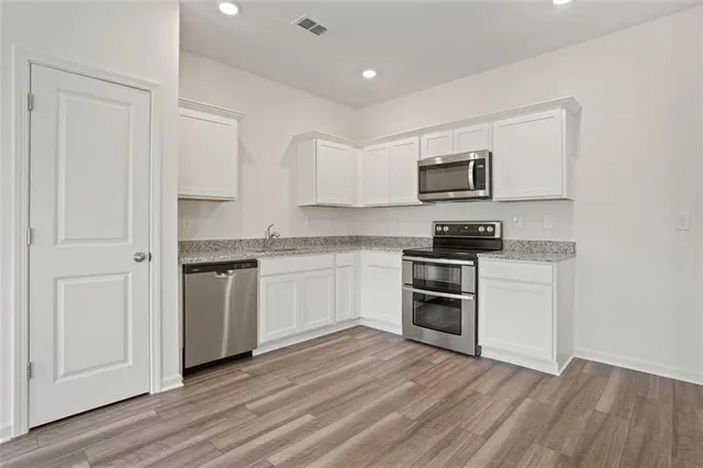 a kitchen with granite countertop white cabinets and stainless steel appliances