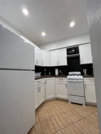 a kitchen with granite countertop a sink a stove and cabinets