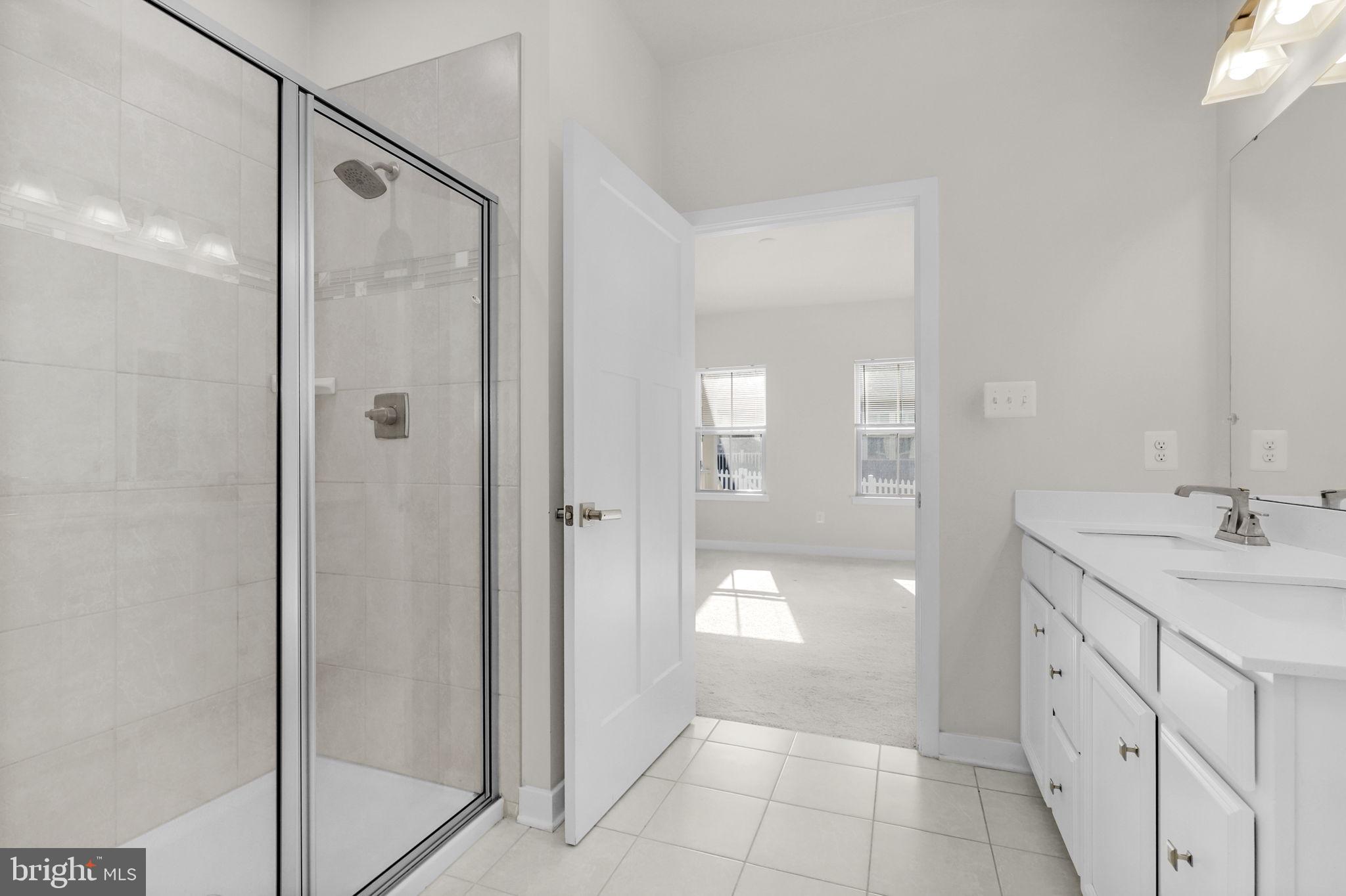 6129 Dock Street Frederick, MD 21703 - Photo 15 of 33 a bathroom with a granite countertop sink a mirror and a shower