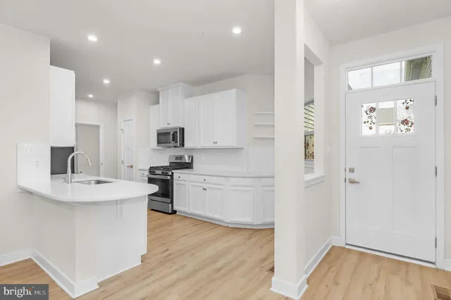 a kitchen with a sink white cabinets and stainless steel appliances