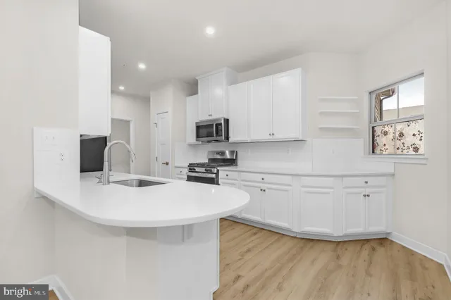 a kitchen with stainless steel appliances a sink a stove a refrigerator cabinets and a dining table