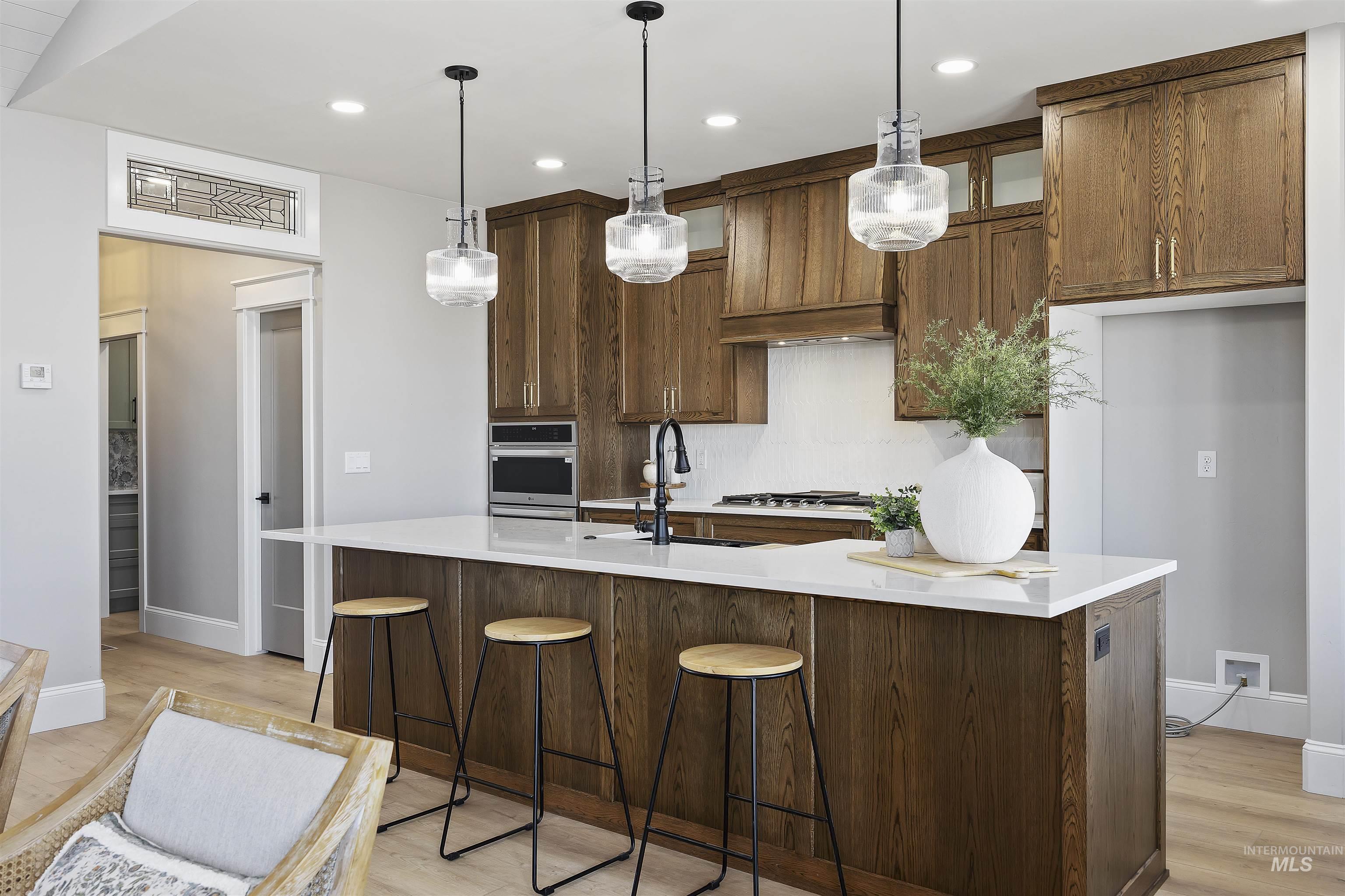 378 West 100 South Rupert, ID 83350 - Photo 12 of 50 Kitchen featuring a large central island with seating, pendant lighting, wood-finish cabinetry, and built-in appliances