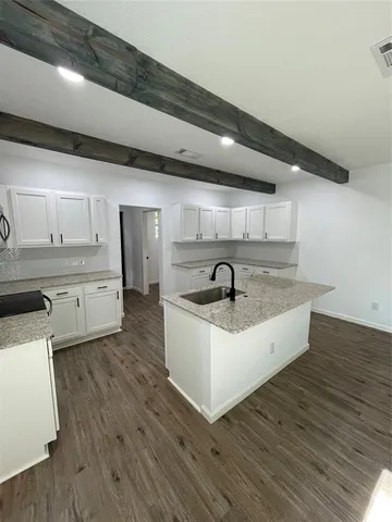 a large white kitchen with sink a refrigerator and white cabinets