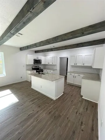 a large kitchen with stainless steel appliances a large counter top a wooden floors and a fireplace