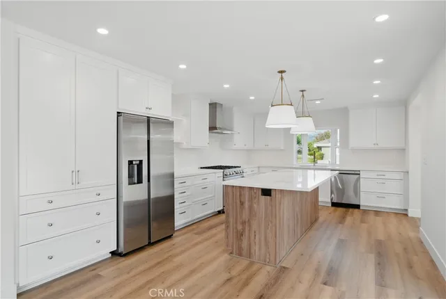 a kitchen with stainless steel appliances granite countertop a kitchen island a stove and a wooden floors