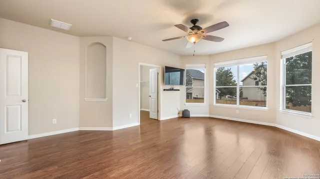 a view of an empty room with a window and wooden floor