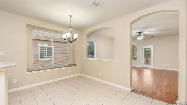a view of an empty room with window and chandelier fan