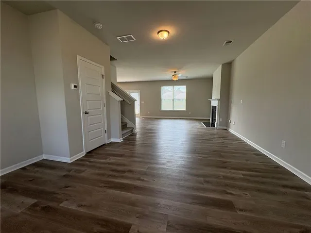 a view of an empty room with window and wooden floor