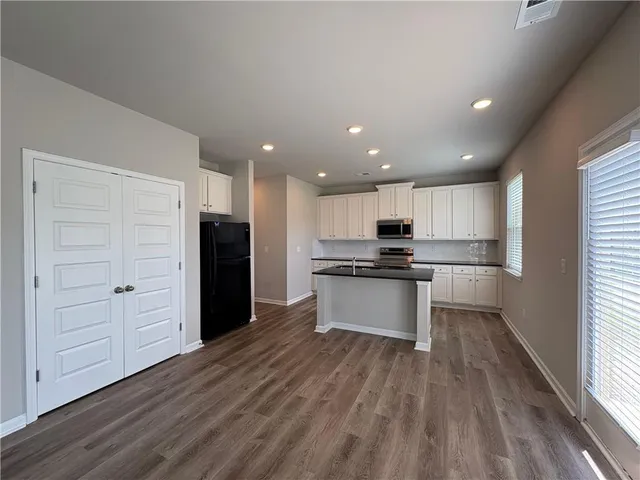 a kitchen with a refrigerator and white cabinets