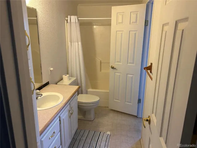 a bathroom with a granite countertop sink toilet and shower a mirror