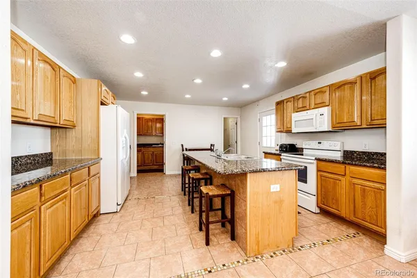 a kitchen with stainless steel appliances granite countertop a stove a sink and a refrigerator