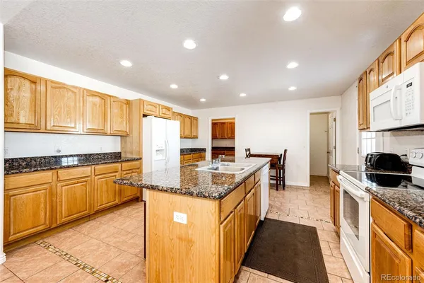 a kitchen with stainless steel appliances granite countertop a stove a refrigerator a oven a sink a dining table and chairs with wooden floor