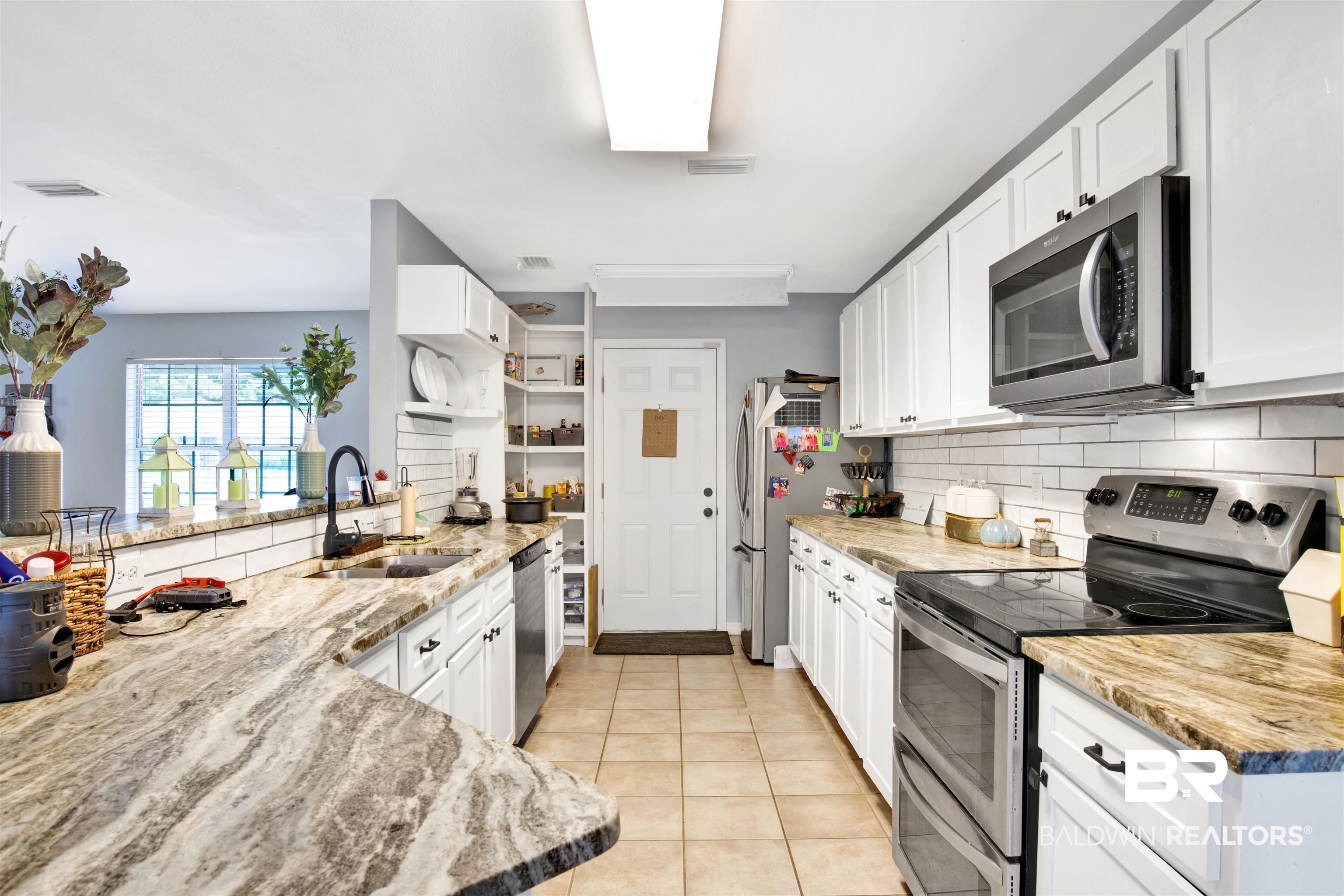 24384 Sailfish Lane Orange Beach, AL 36561 - Photo 7 of 23 Kitchen featuring sink, stainless steel appliances, white cabinets, and tasteful backsplash