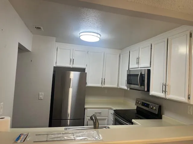 a kitchen with stainless steel appliances granite countertop a refrigerator and a stove top oven