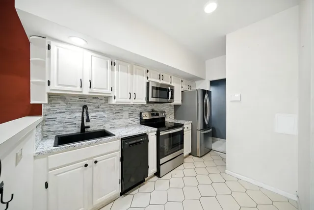 a kitchen with granite countertop a sink a stove top oven and stainless steel appliances