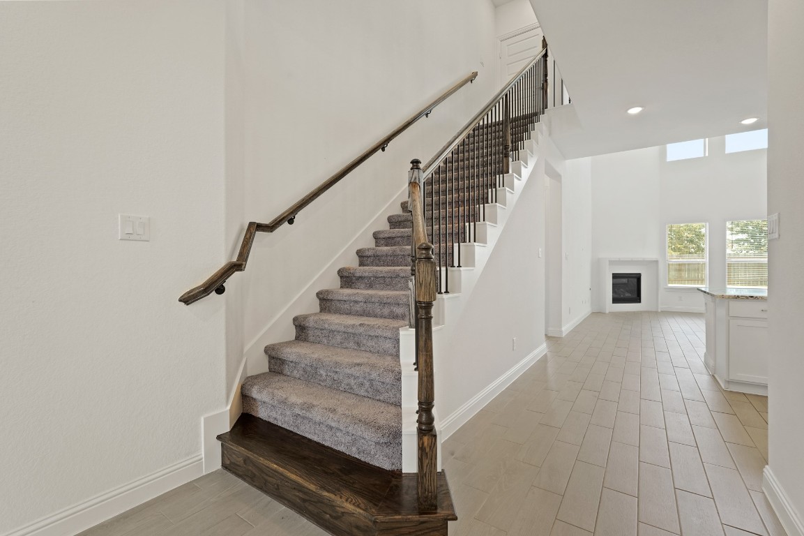 8010 Chantilly Manor Fulshear, TX 77441 - Photo 13 of 50 This elegant staircase with wrought iron spindles and wood accents leads to the upstairs game room, media room, and three spacious bedrooms.
