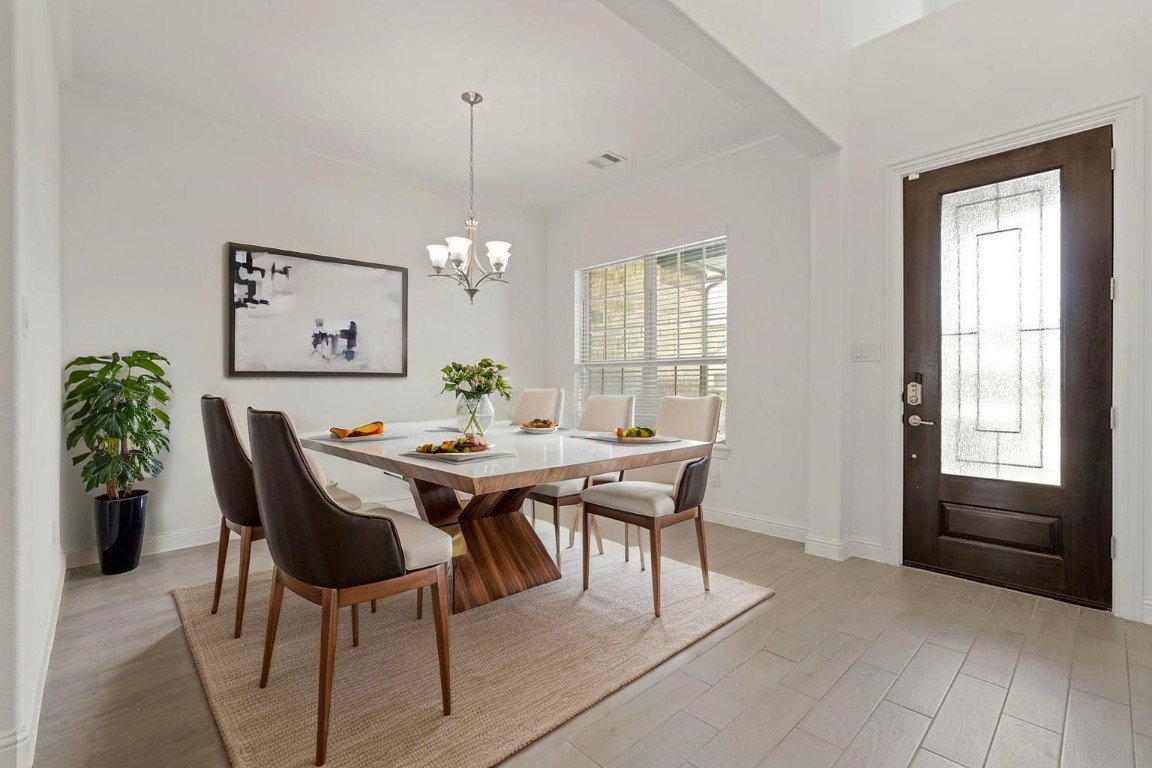 8010 Chantilly Manor Fulshear, TX 77441 - Photo 7 of 50 This elegantly staged dining room features a modern table setting, chic artwork, and abundant natural light, creating a warm and inviting space for entertaining.