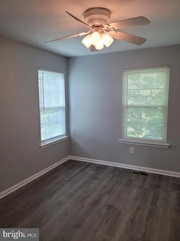 en empty room with windows and chandelier fan