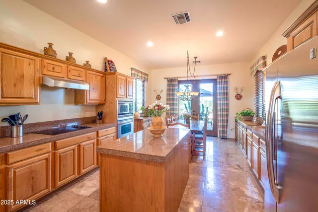 a kitchen with stainless steel appliances granite countertop a stove a sink dishwasher and a refrigerator with wooden floor