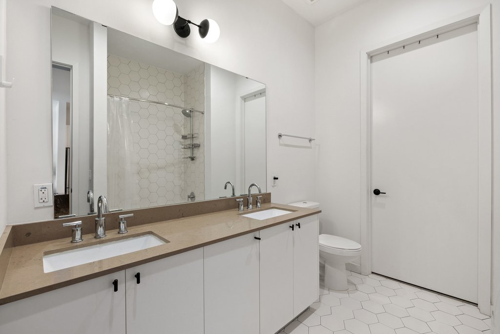 800 Embassy Drive, Unit 413 Austin, TX 78702 - Photo 11 of 27 Full bath with double vanity, a shower with curtain, and light tile patterned flooring