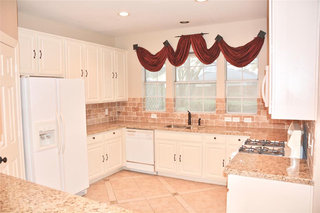View of the kitchen with granite counter tops, pantry and an included refrigerator.