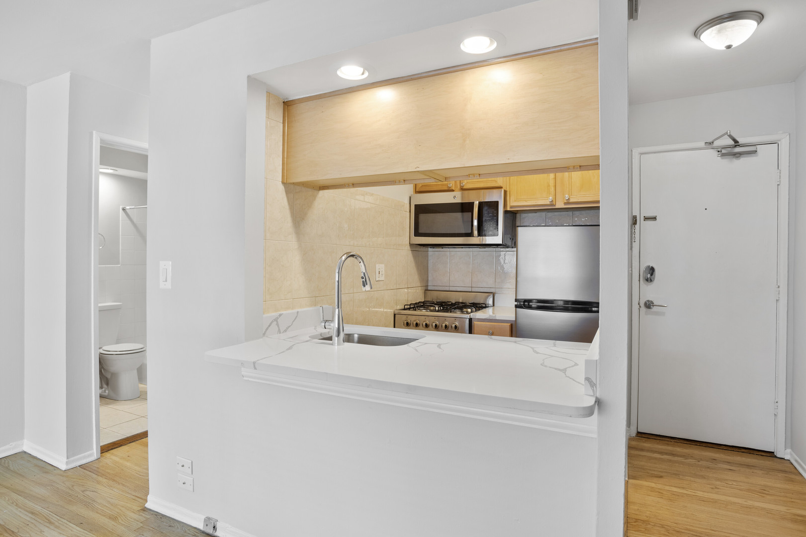 6758 North Sheridan Road, Unit 438 Chicago, IL 60626 - Photo 2 of 12 a kitchen with a sink appliances and wooden floor