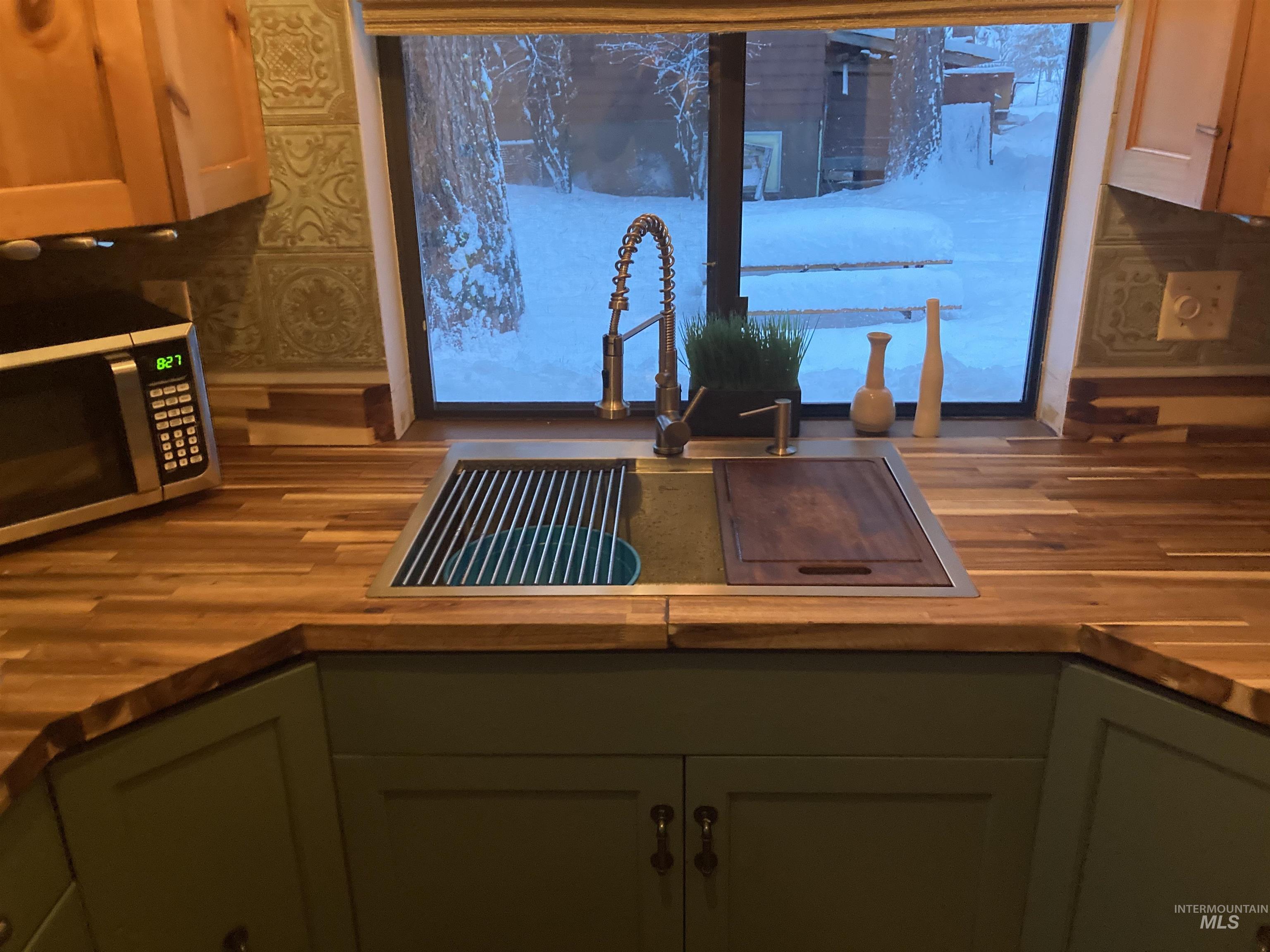 306 Rio Vista Boulevard McCall, ID 83638 - Photo 16 of 40 Kitchen with green cabinets, stainless steel microwave, butcher block countertops, and wallpapered walls