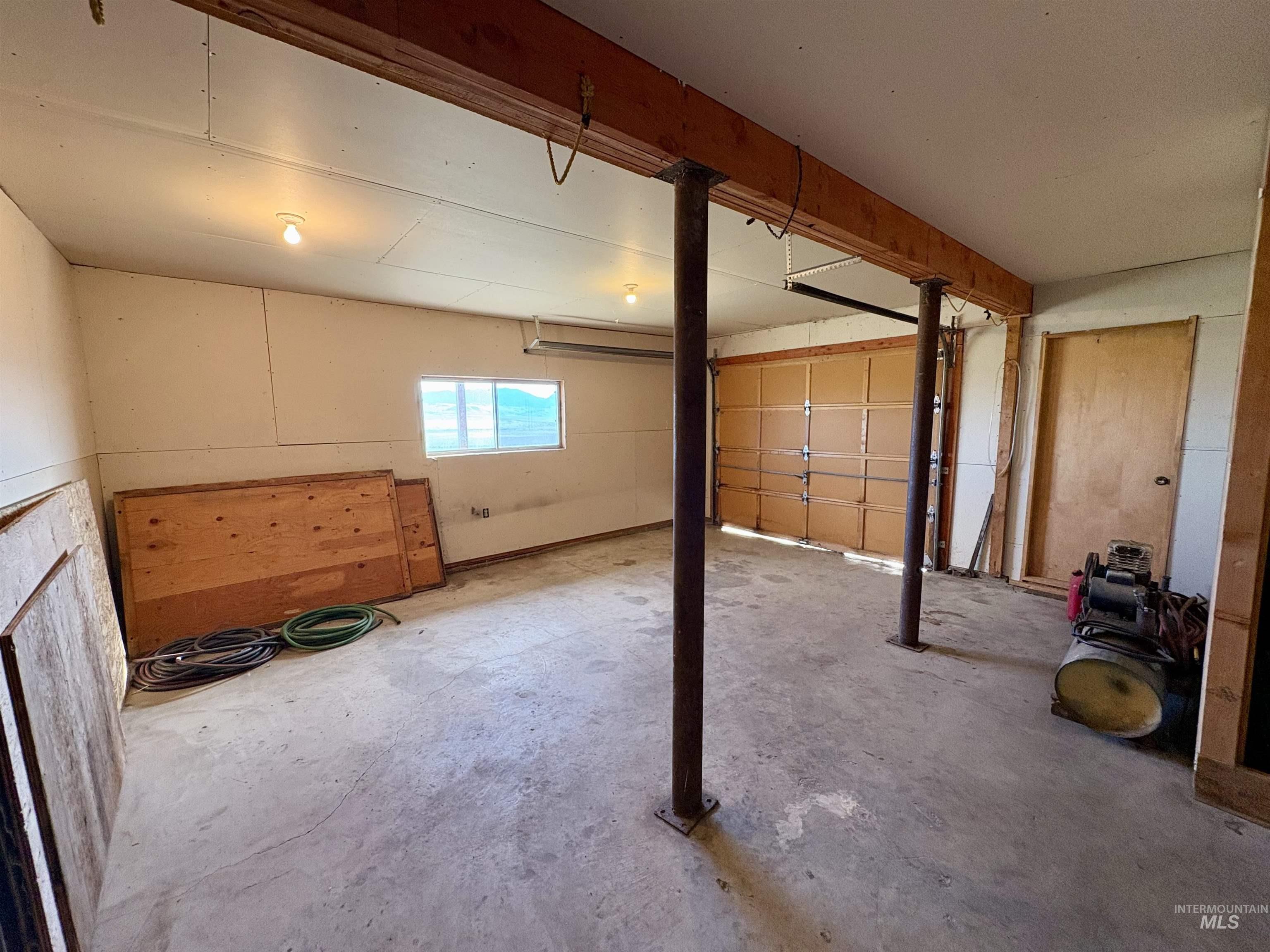 2040 Pahsimeroi River Road May, ID 83253 - Photo 22 of 29 Spacious garage featuring a concrete floor, overhead lighting, a single window, an overhead garage door, and a wooden access door