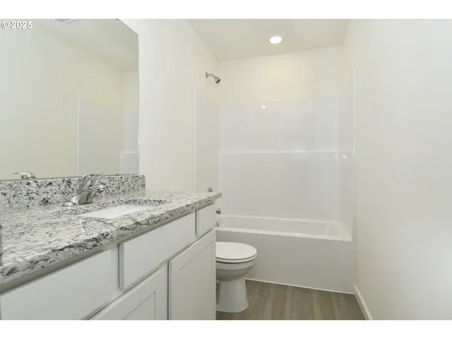 a bathroom with a granite countertop sink a toilet and shower