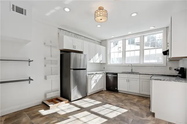 a kitchen with granite countertop a refrigerator stove top oven and sink