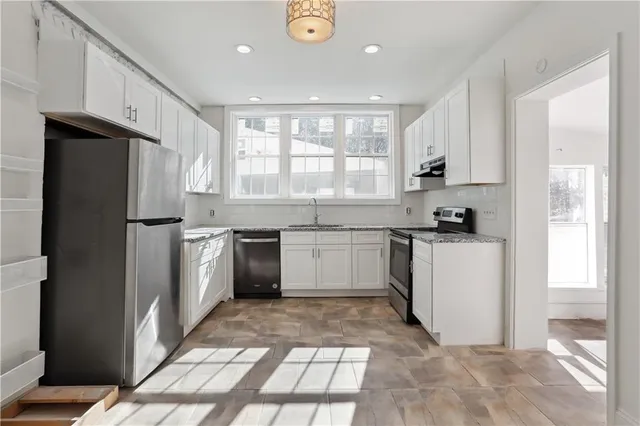 a kitchen with a sink a refrigerator and white cabinets