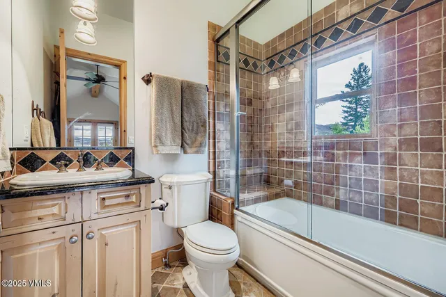 a bathroom with a granite countertop sink a toilet and shower