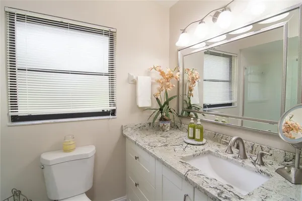 a bathroom with a granite countertop sink toilet and mirror