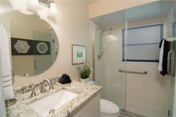 a bathroom with a granite countertop sink toilet and shower