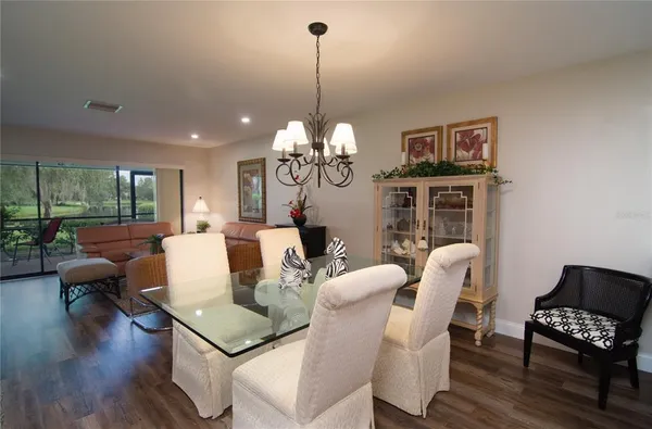 a living room with couches a fireplace and a dining table with wooden floor