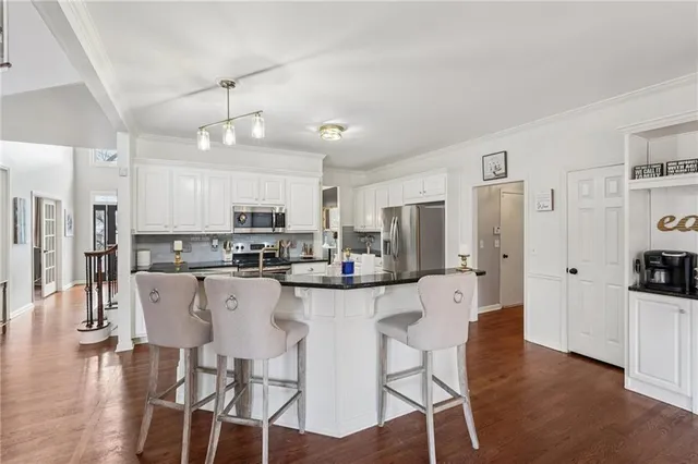 a kitchen with stainless steel appliances a dining table chairs refrigerator and sink