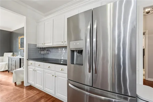 a kitchen with stainless steel appliances granite countertop a refrigerator and white cabinets