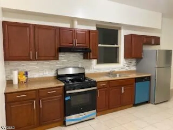 a kitchen with stainless steel appliances granite countertop a stove a sink and a refrigerator with wooden cabinets