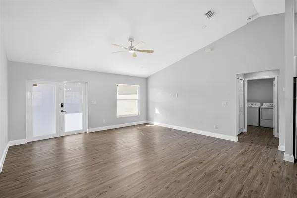 a view of an empty room with window and wooden floor