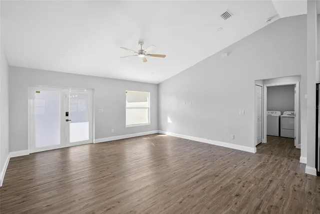 a view of an empty room with window and wooden floor