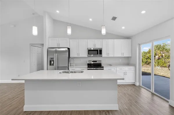 a large kitchen with stainless steel appliances kitchen island a large counter top and a wooden floors