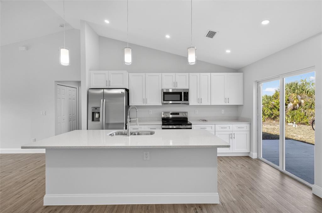 375 Denver Drive Port Charlotte, FL 33954 - Photo 8 of 37 a large kitchen with stainless steel appliances kitchen island a large counter top and a wooden floors