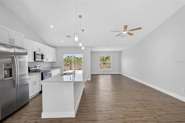 a living room with stainless steel appliances kitchen island hardwood floor and a window