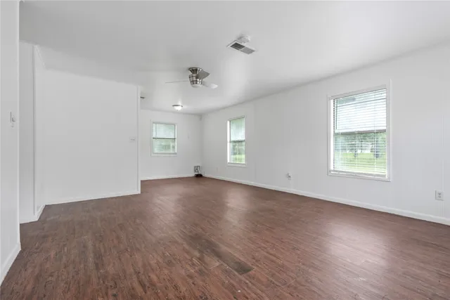 an empty room with wooden floor and windows
