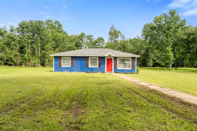 a view of a house with backyard and tree