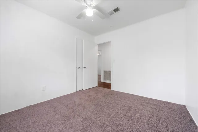 an empty room with a ceiling fan and carpet