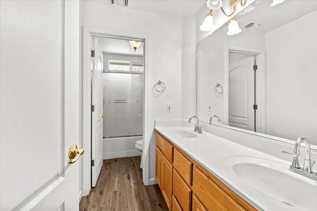 a bathroom with a double vanity sink a large mirror a shower and bathtub