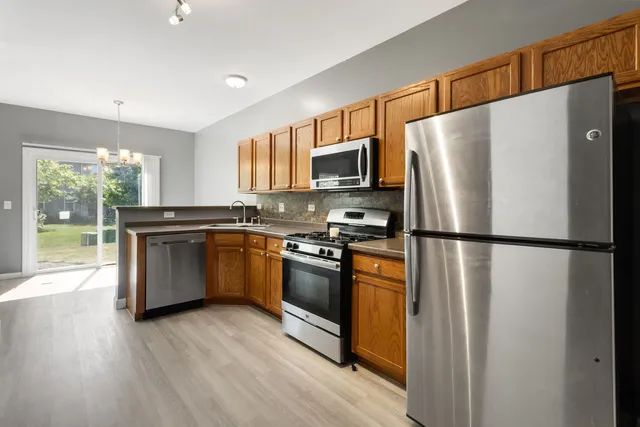 a kitchen with stainless steel appliances a refrigerator a stove a sink a center island and a window